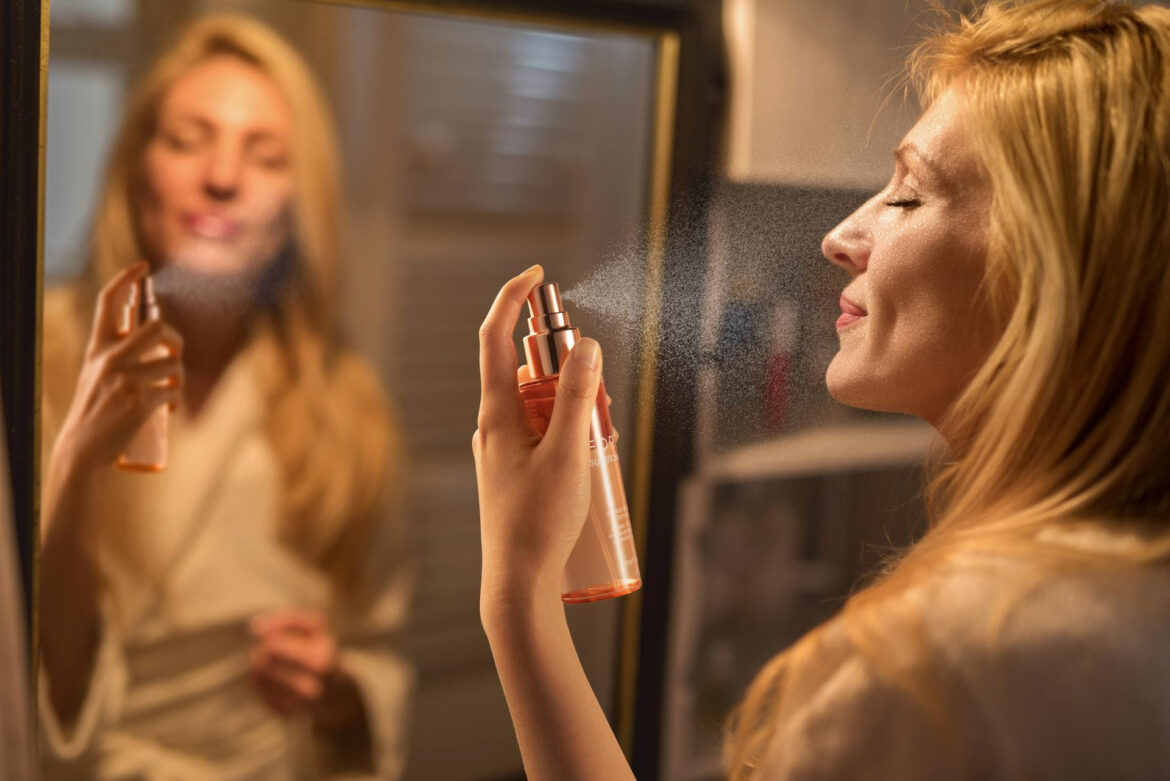 mid adult woman in the bathroom applying perfume with eyes closed.